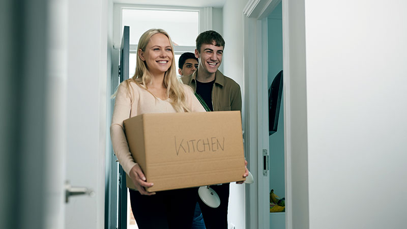 Students moving in to a new flat carrying boxes